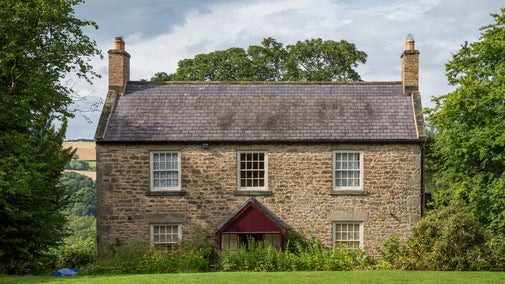 Close square-on view of the new farmhouse at Cherryburn built by Thomas Bewick's brother in late 1820's showing dressed sandstone construction, with slated roof, brick chimneys and a front porch.
